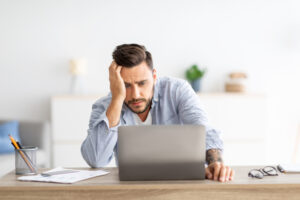 Freelance Stress. Male Freelancer Tired After Work On Laptop At Home, Having Problems With Project, Sitting At Workplace